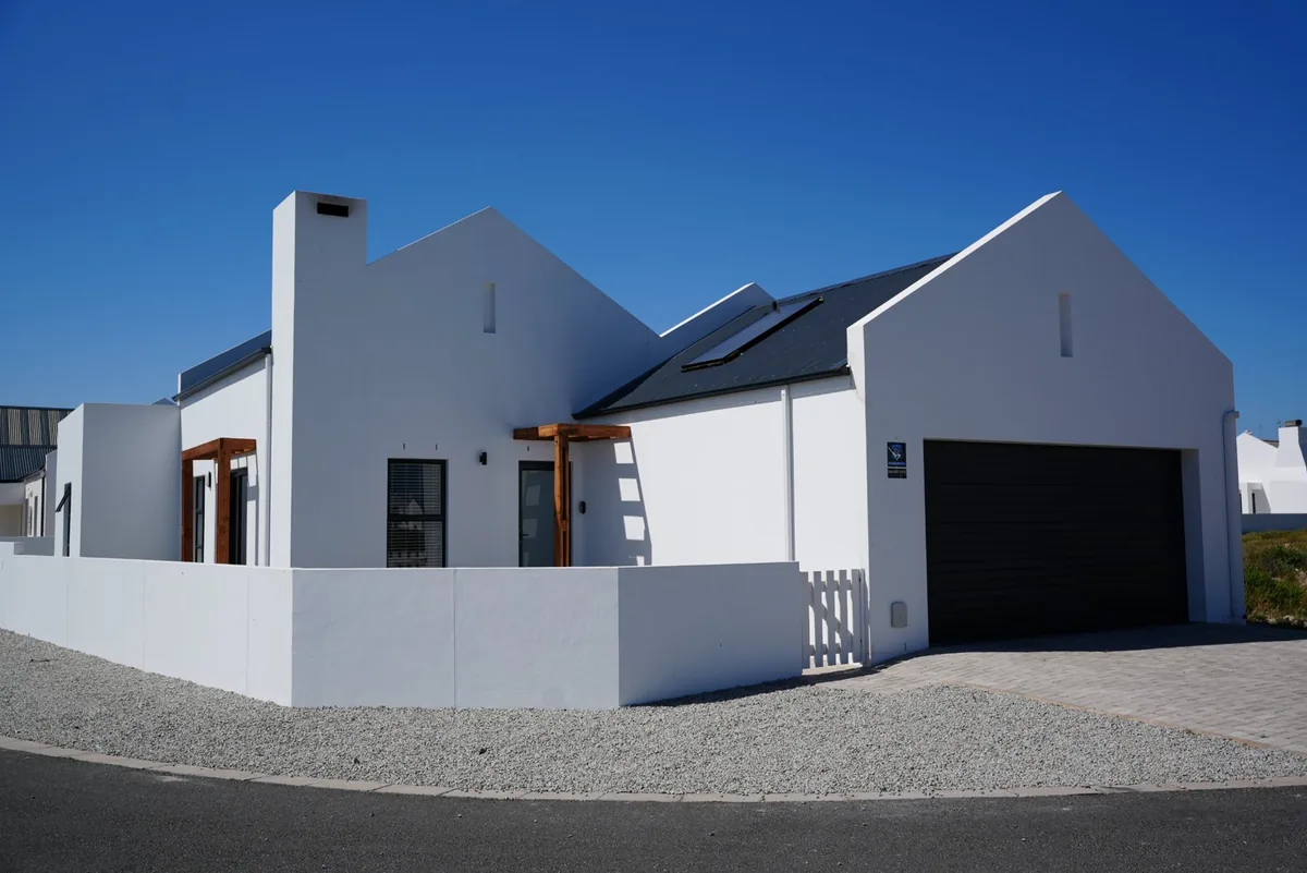 Britannia Breeze from the street: white gables, a timber pergola at the front door and a dark garage door.