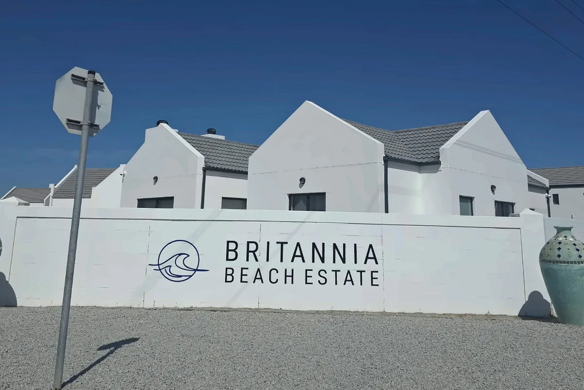 The Britannia Beach Estate entrance wall with white gables behind, flanked by two ceramic urns.